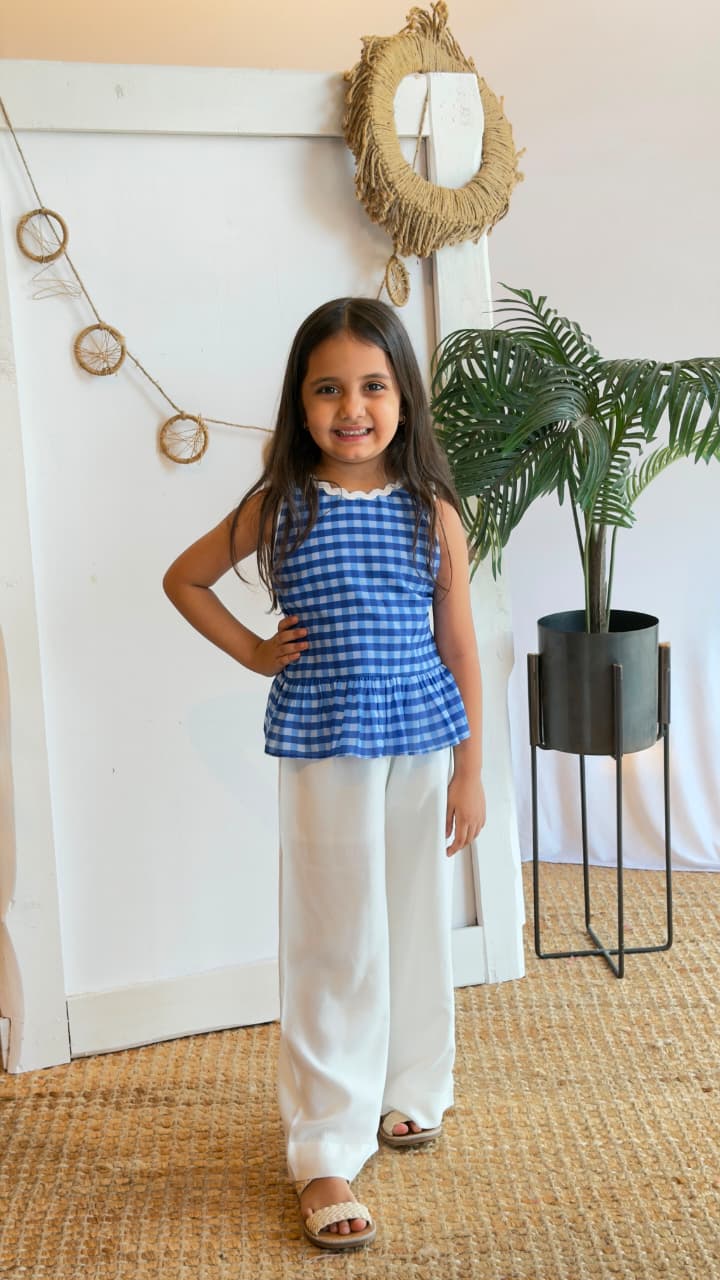 Girl modelling a blue gingham peplum co-ord set with white palazzo pants