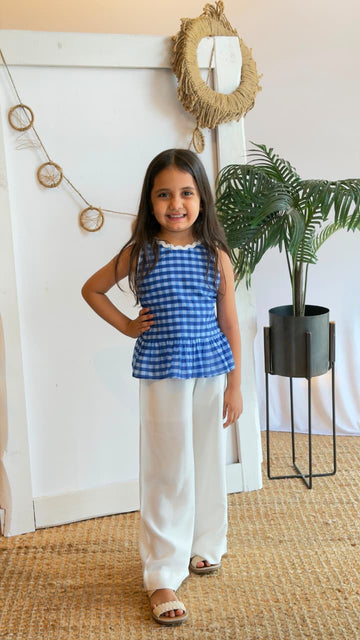 Girl modelling a blue gingham peplum co-ord set with white palazzo pants
