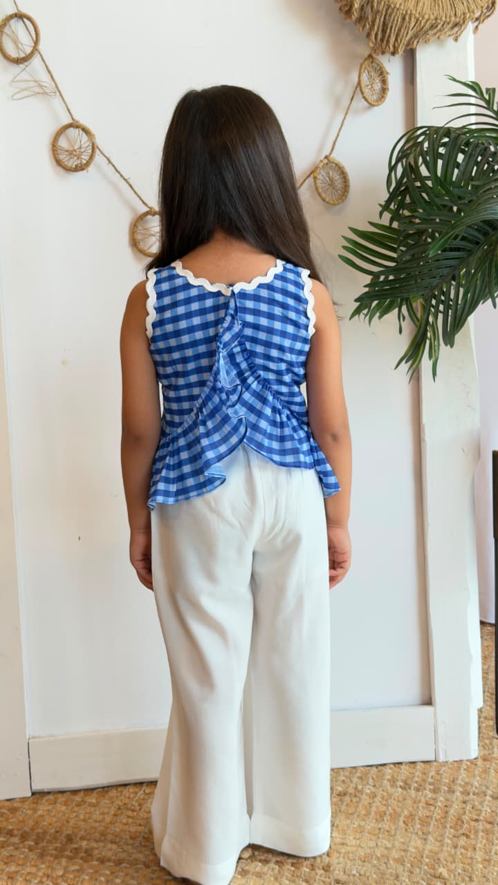Girl wearing a blue gingham peplum top with white palazzo pants