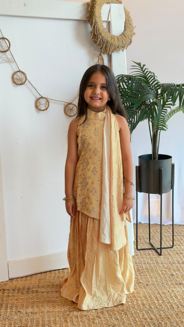Girl wearing a golden sleeveless kurta with flared sharara bottoms and dupatta