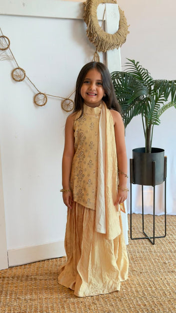 Girl wearing a golden sleeveless kurta with flared sharara bottoms and dupatta