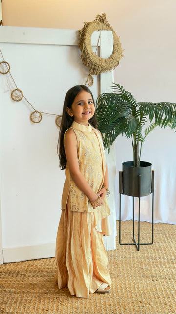 Back view of a girl wearing a golden kurta sharara set with dupatta