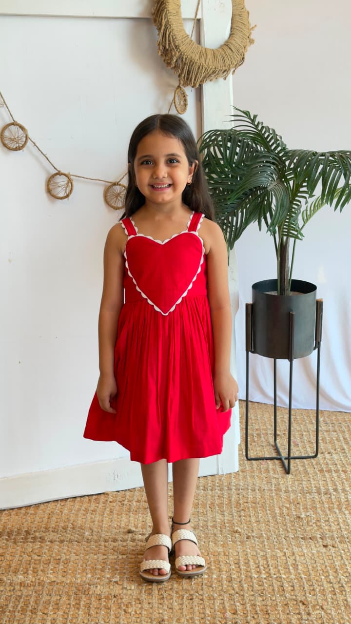 Girl wearing a red heart detail dress while holding a flower