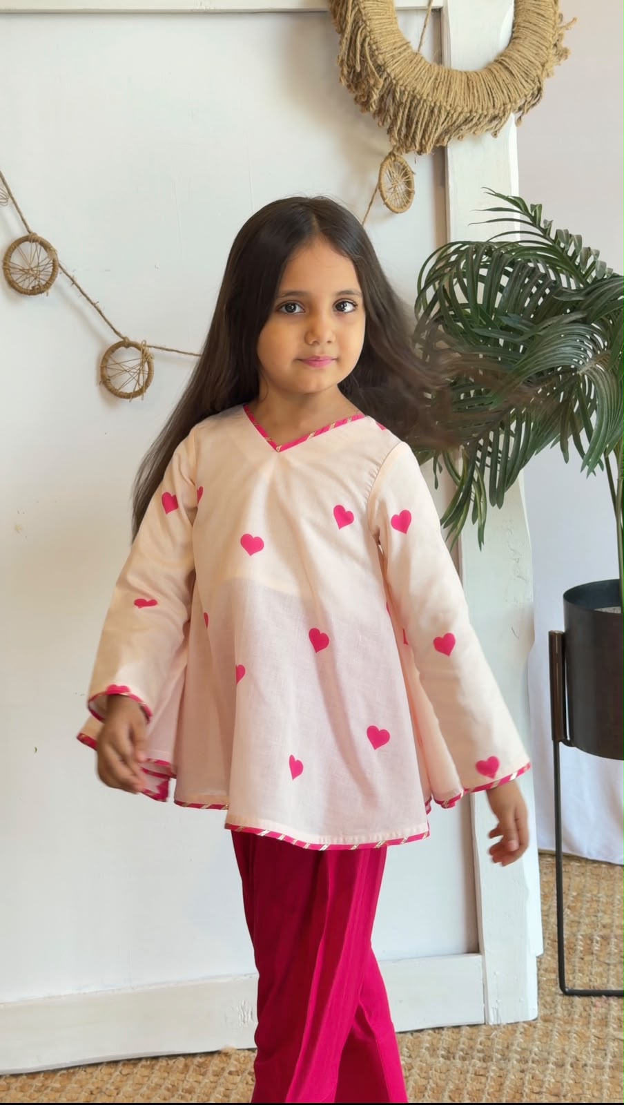 Side view of a girl wearing a blush heart-print top and pink pants