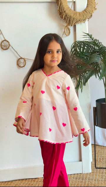 Side view of a girl wearing a blush heart-print top and pink pants