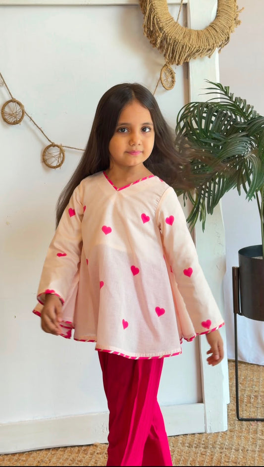 Side view of a girl wearing a blush heart-print top and pink pants