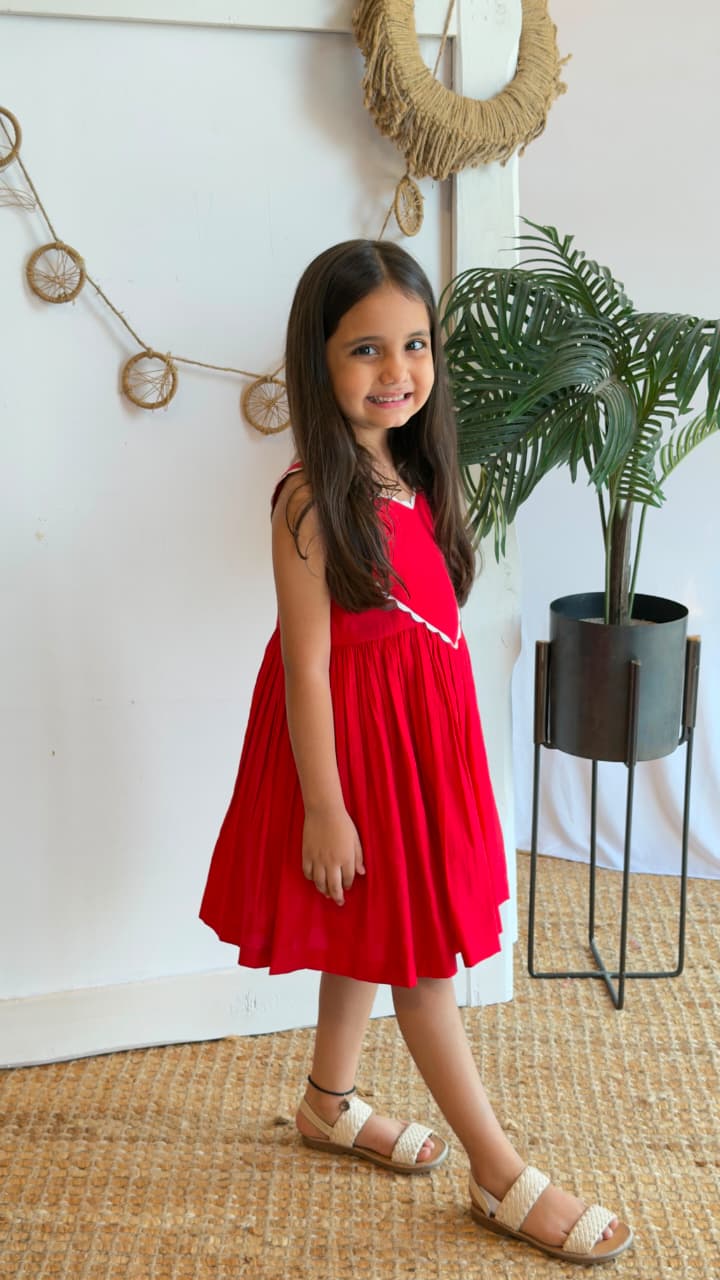 Front view of a red girls dress with a heart-shaped front detail and scalloped trim