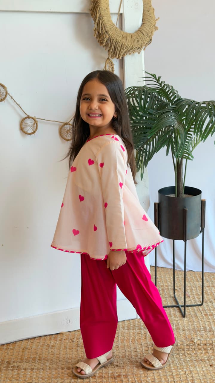 Back view of a blush heart-print flared top with matching pink pants