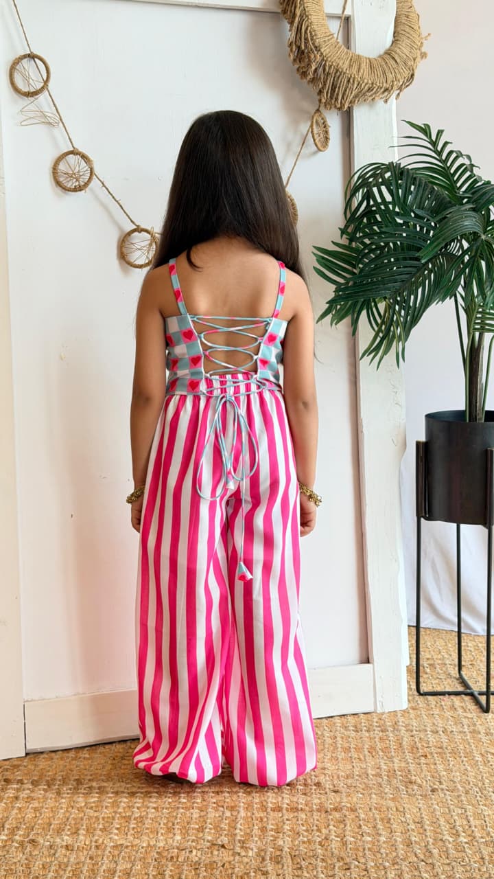 Girl wearing a mint gingham heart-print top with lace-up back and pink striped palazzo pants, back view