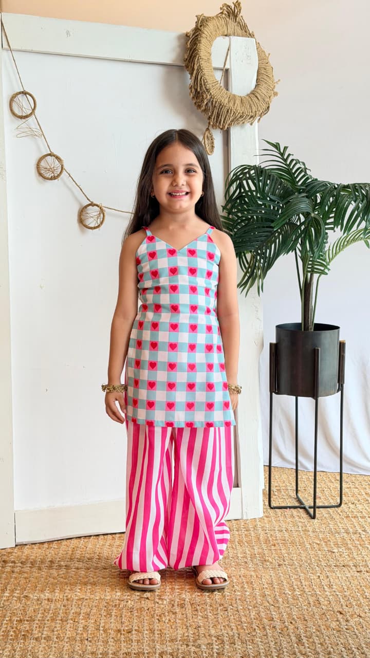 Girl wearing a mint gingham heart-print top with pink striped palazzo pants, front view