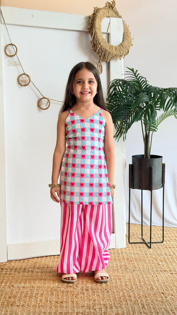 Girl wearing a mint gingham heart-print top with pink striped palazzo pants, front view