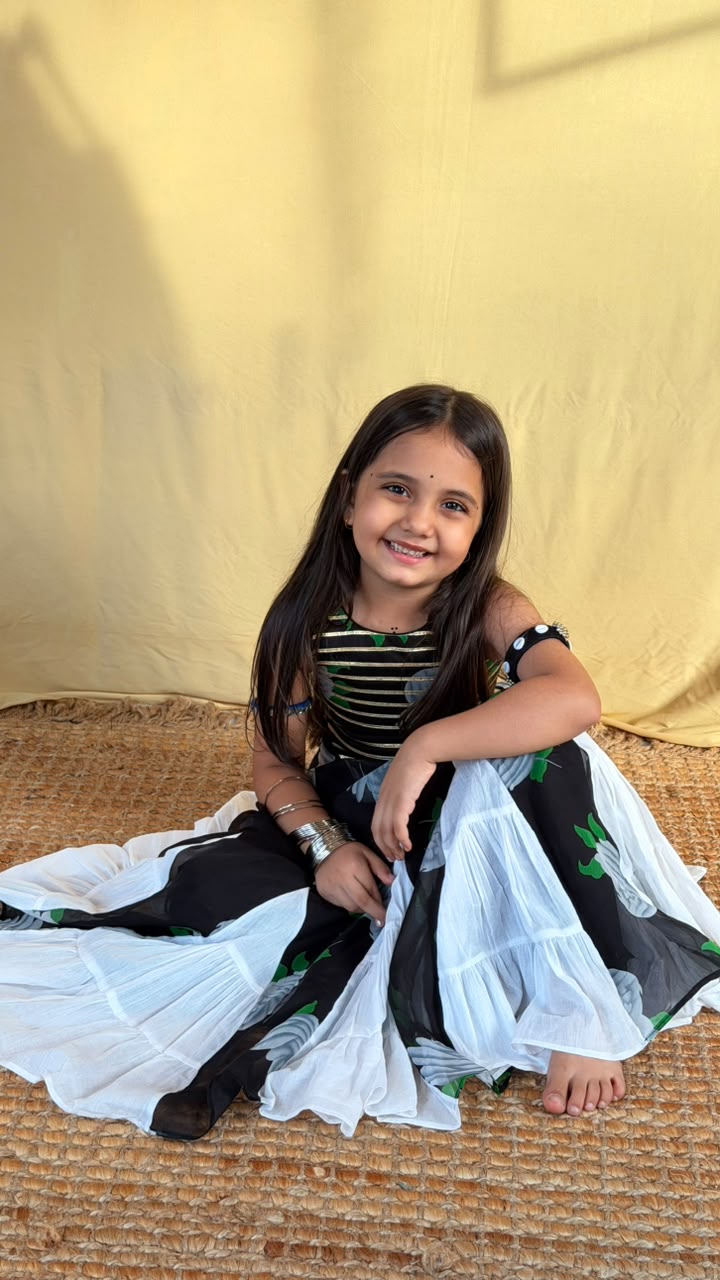 Full-length view of a girl wearing a black floral lehenga skirt with white panels and a striped top