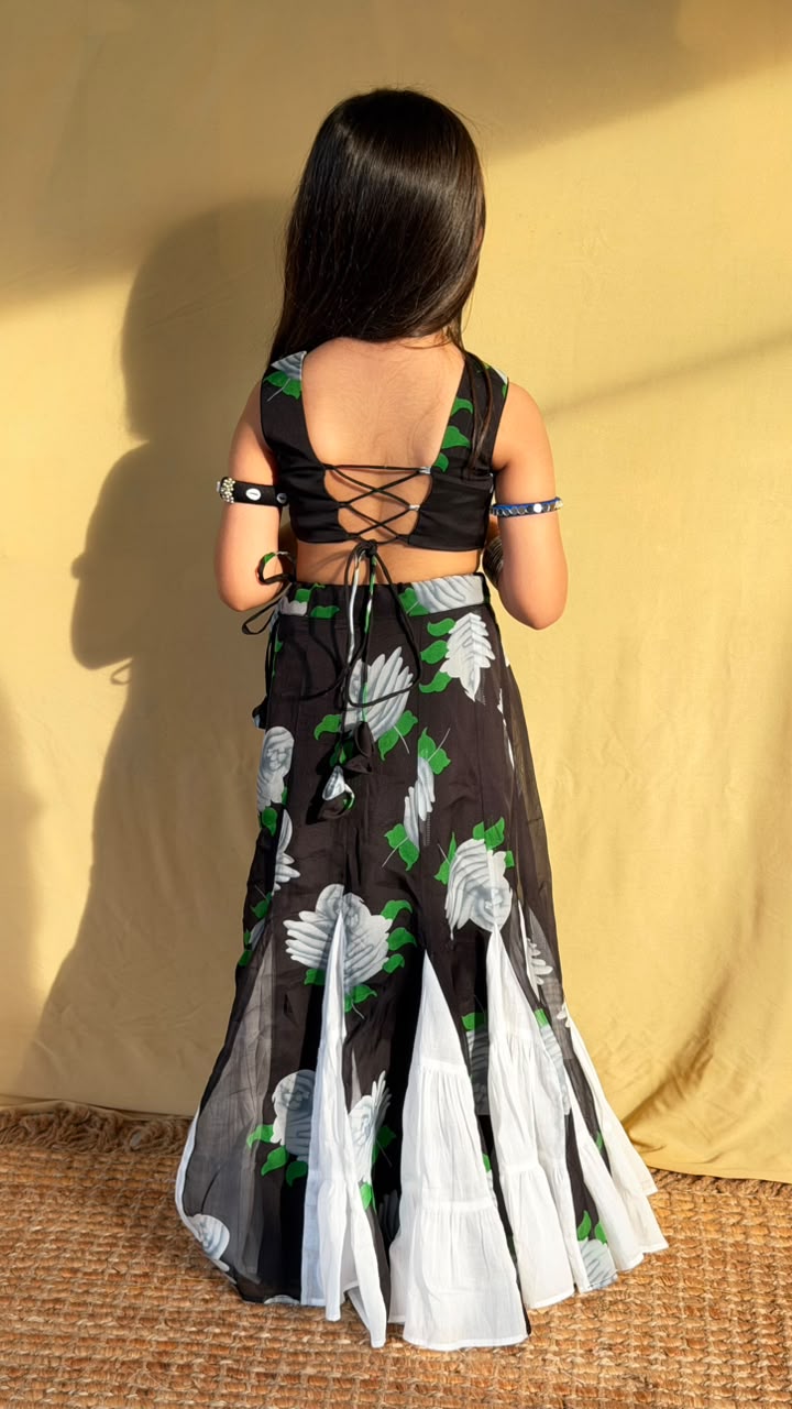 Seated view of a girl wearing the black and white floral lehenga set