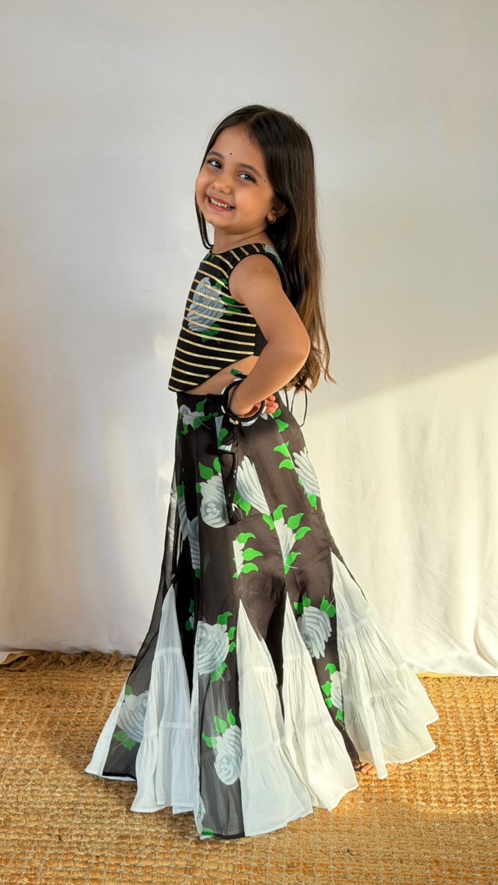 Front view of a girl wearing a black floral lehenga skirt with a striped cropped top